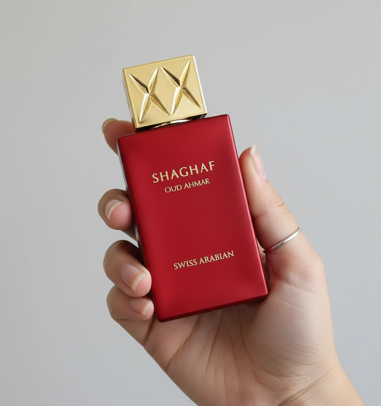 alt="Parfum Shaghaf Oud Ahmar tenu dans une main, mettant en valeur le flacon"