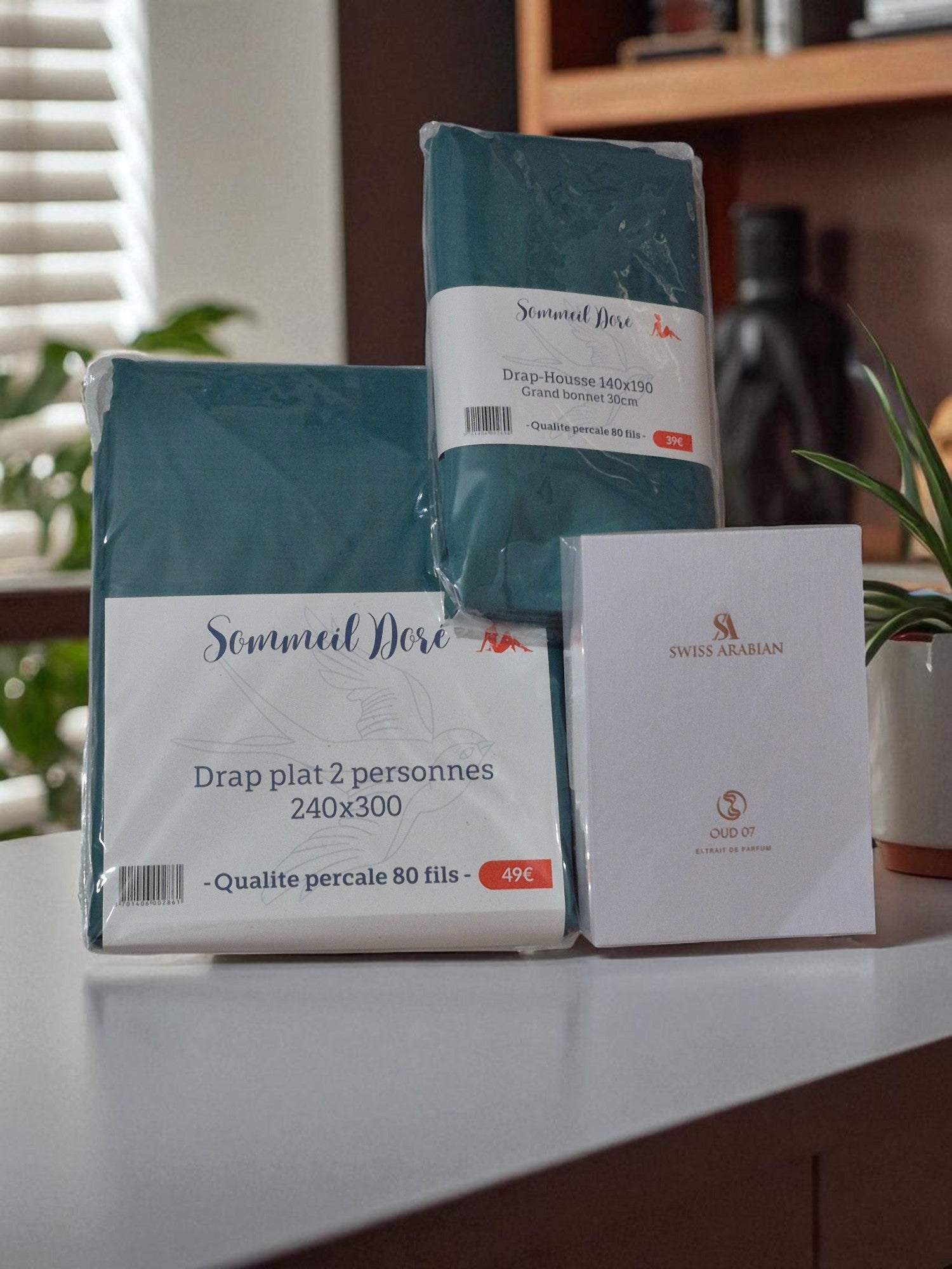 Coffret de linge de lit bleu canard comprenant drap plat, drap housse et taies d’oreiller, présenté plié