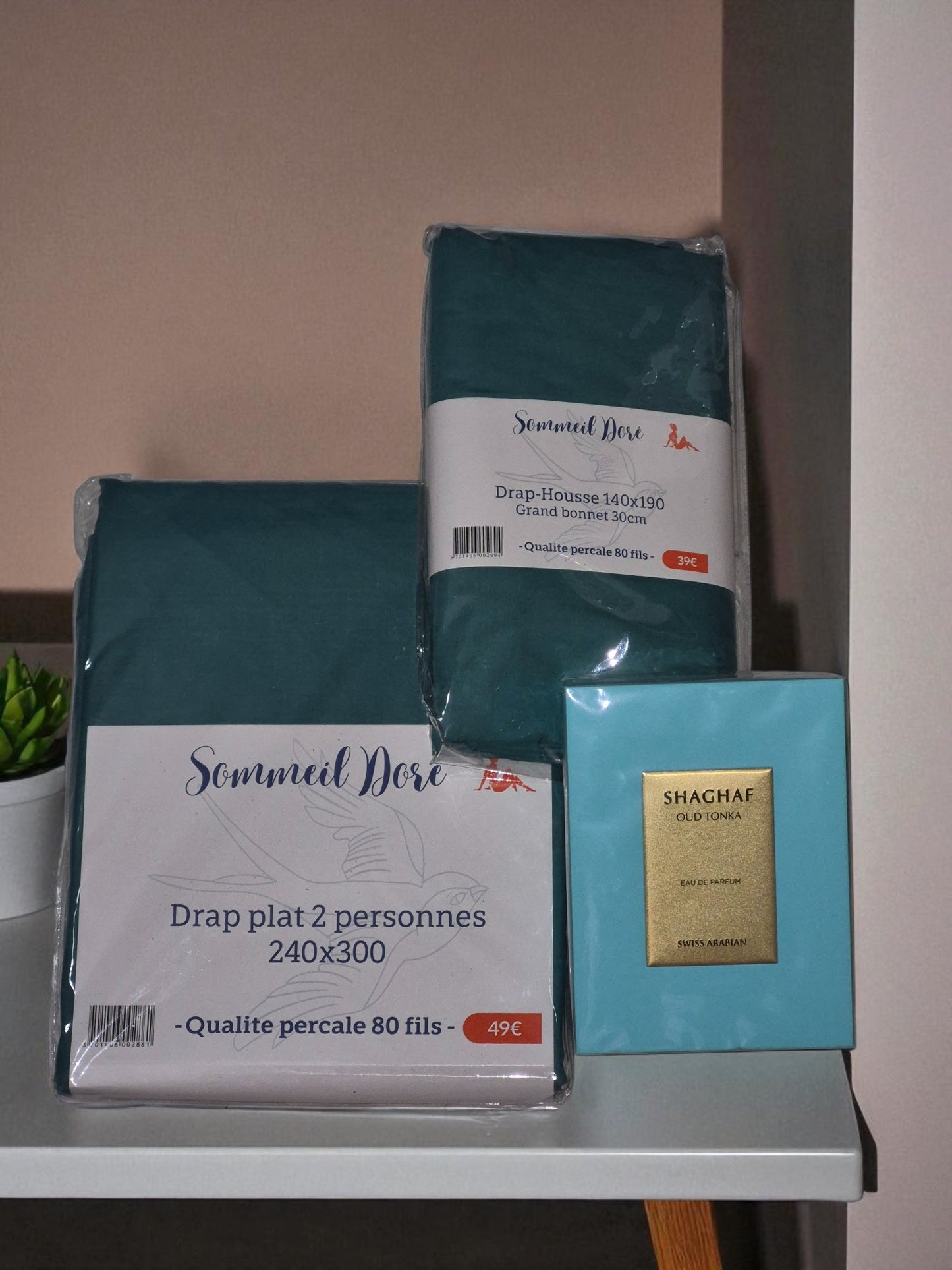 Coffret linge de lit vert avec drap plat, drap housse et coffret parfum décoratif posé sur table