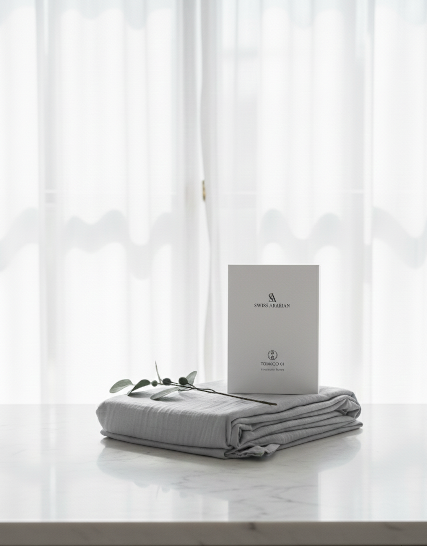 Coffret parfum Swiss Arabian présenté sur un lit avec drap en coton blanc, ambiance cosy et raffinée