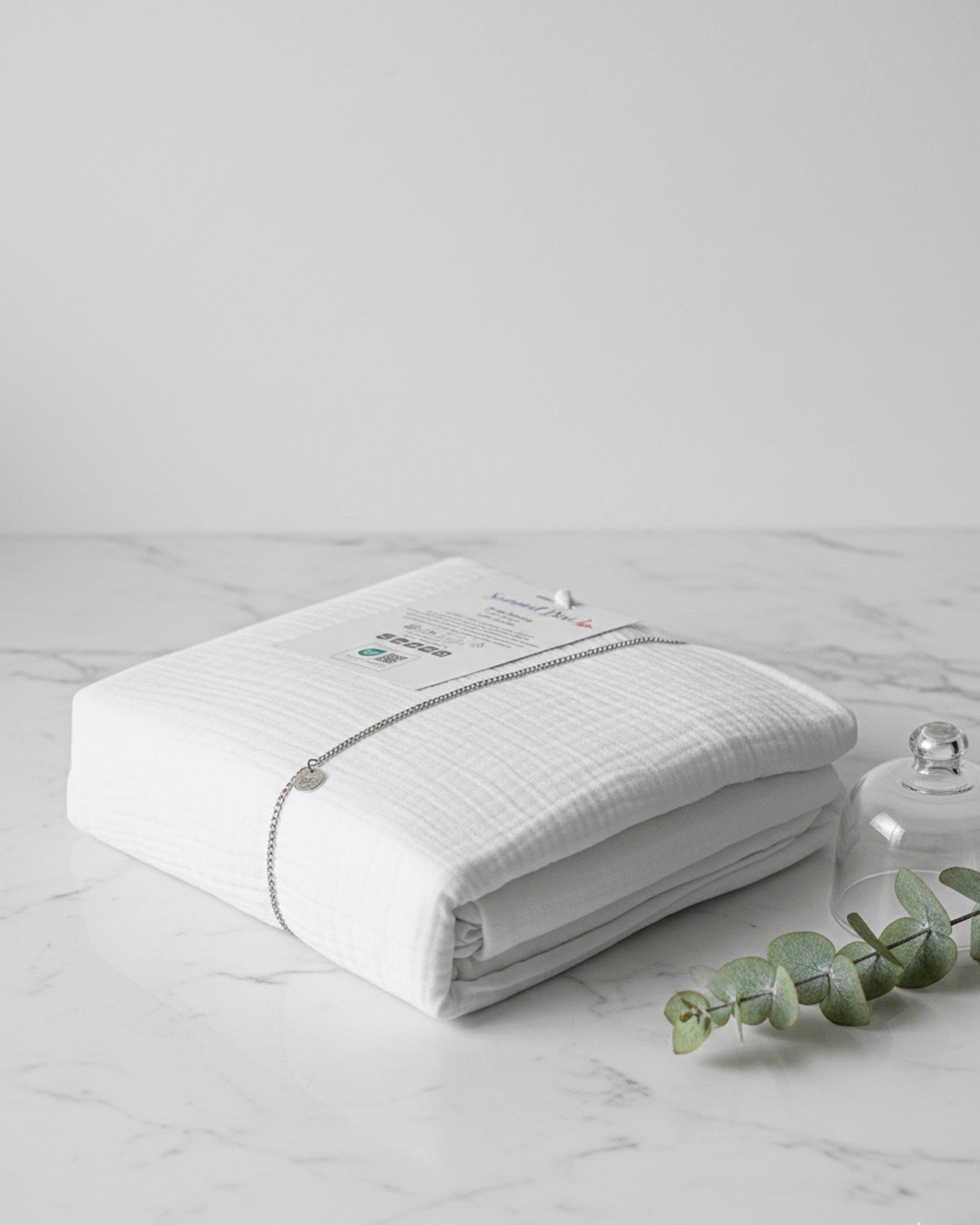 Drap housse en gaze de coton blanc plié avec étiquette, texture douce et naturelle