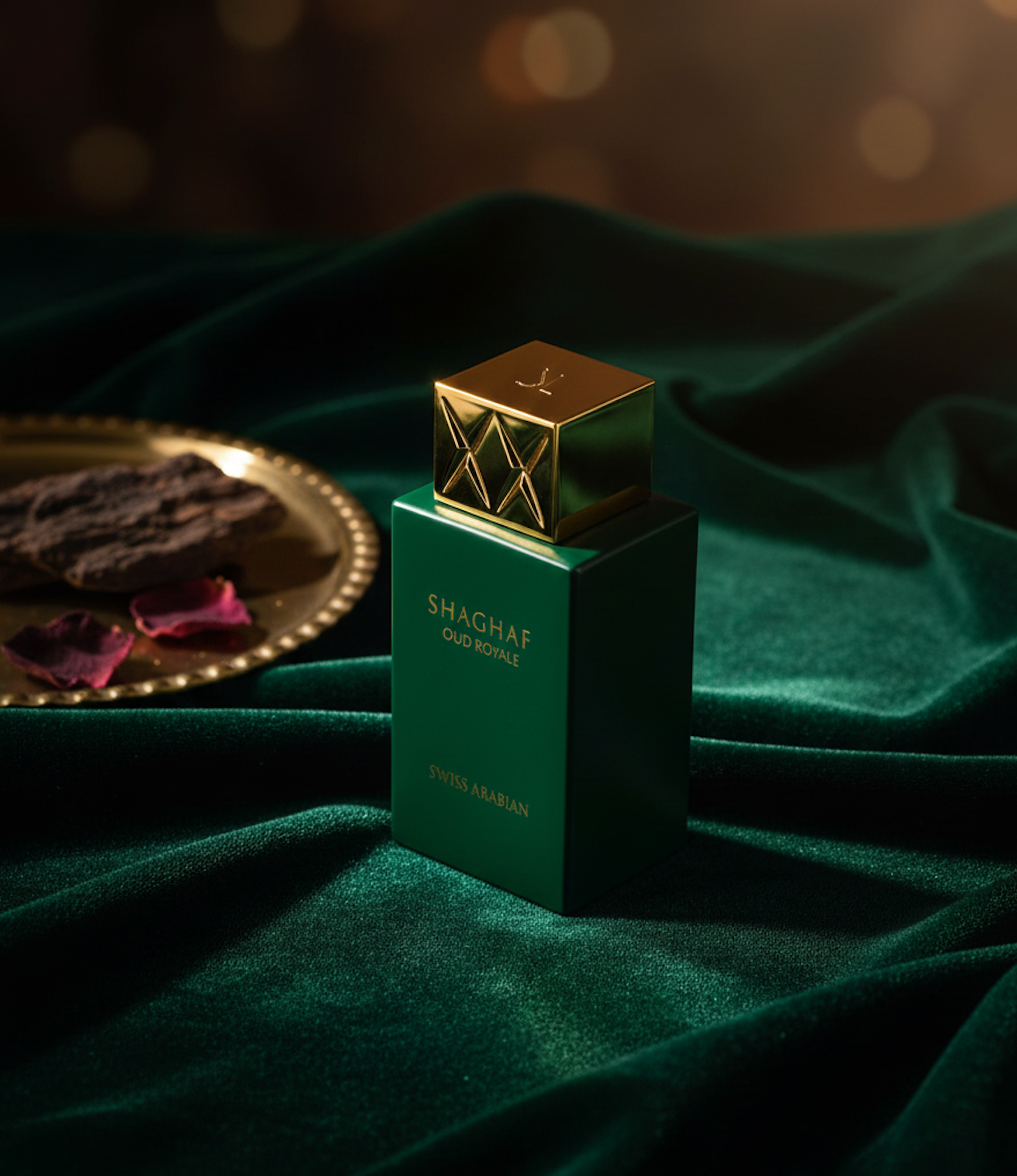 Flacon Shaghaf Oud Royale posé sur un tissu vert en velours avec un éclairage doré luxueux.
