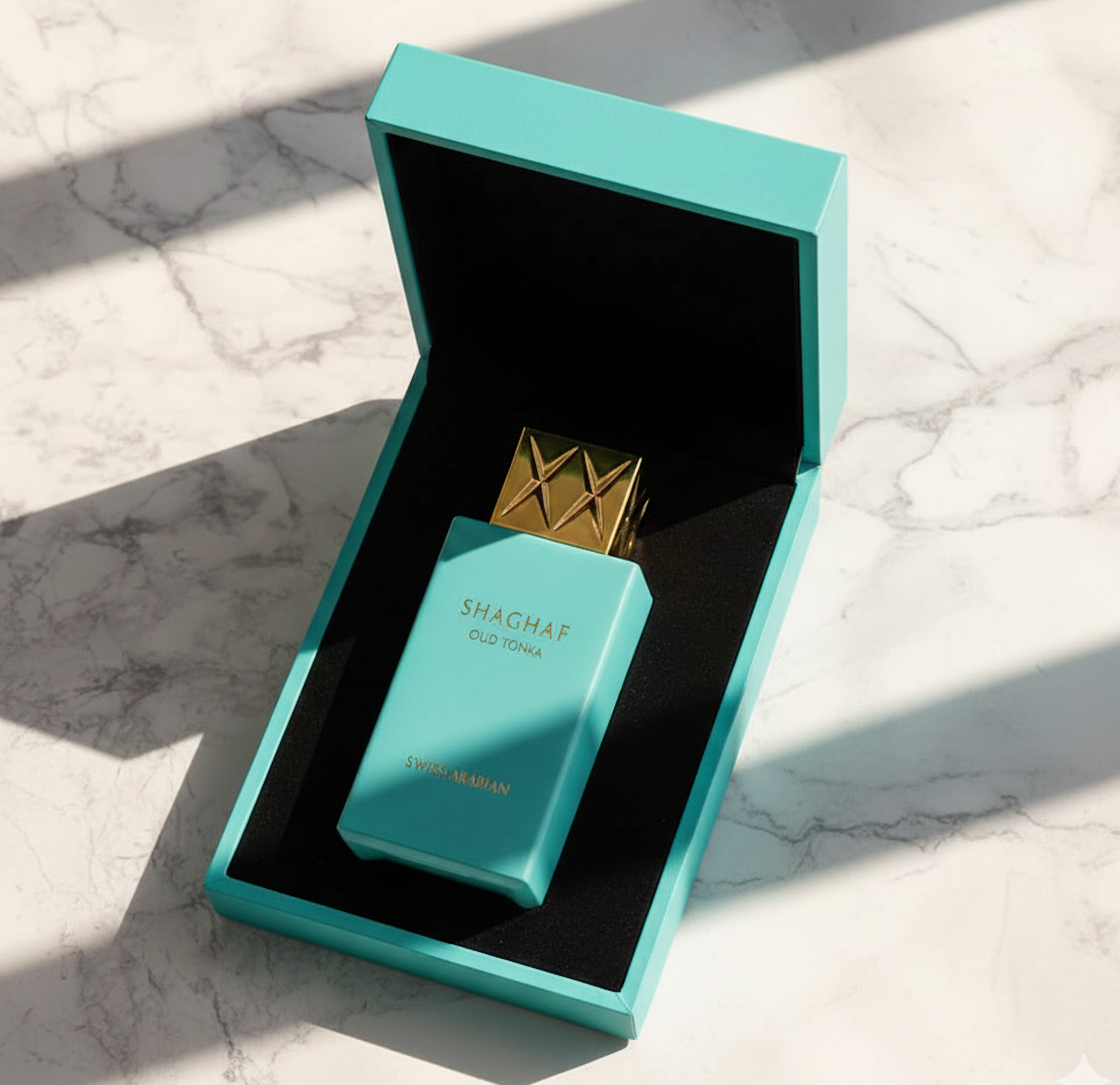 Coffret Shaghaf Oud Tonka ouvert et fermé avec flacon turquoise et capuchon doré sur table en marbre.