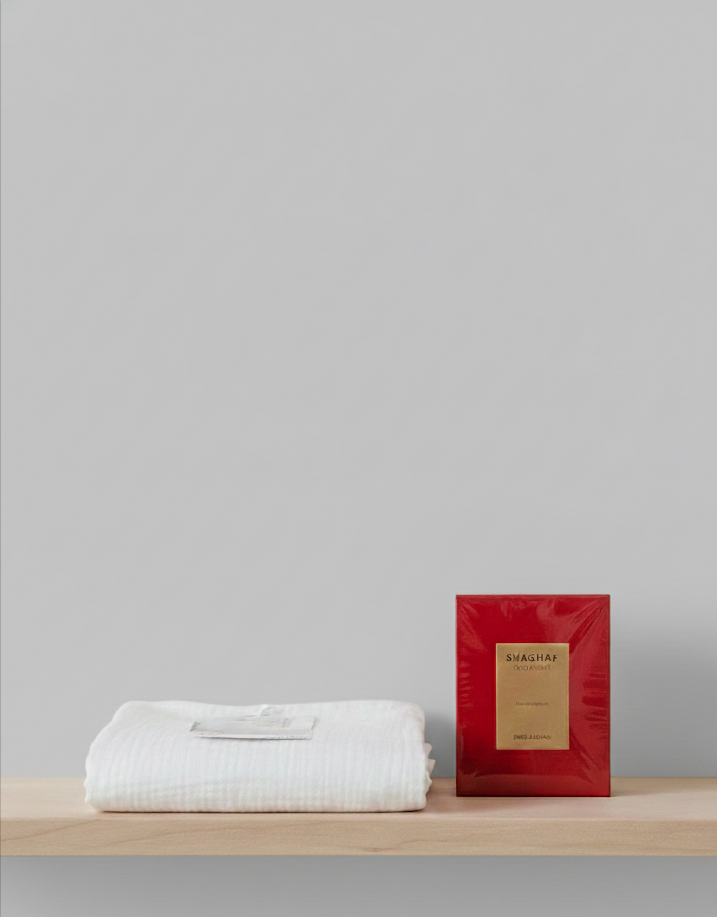 Parfum Shaghaf de Swiss Arabian dans son coffret rouge, posé sur un linge blanc dans une ambiance minimaliste et lumineuse